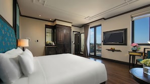 A hotel room with a large bed, a desk with a chair, a TV mounted on the wall, and a balcony with a view. - Silkian Hoian Boutique Hotel & Spa (Da Nang)