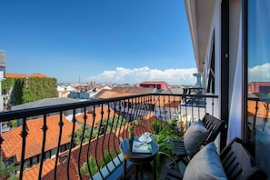 Enjoy the city view from this balcony with a table, book, and comfortable seating.