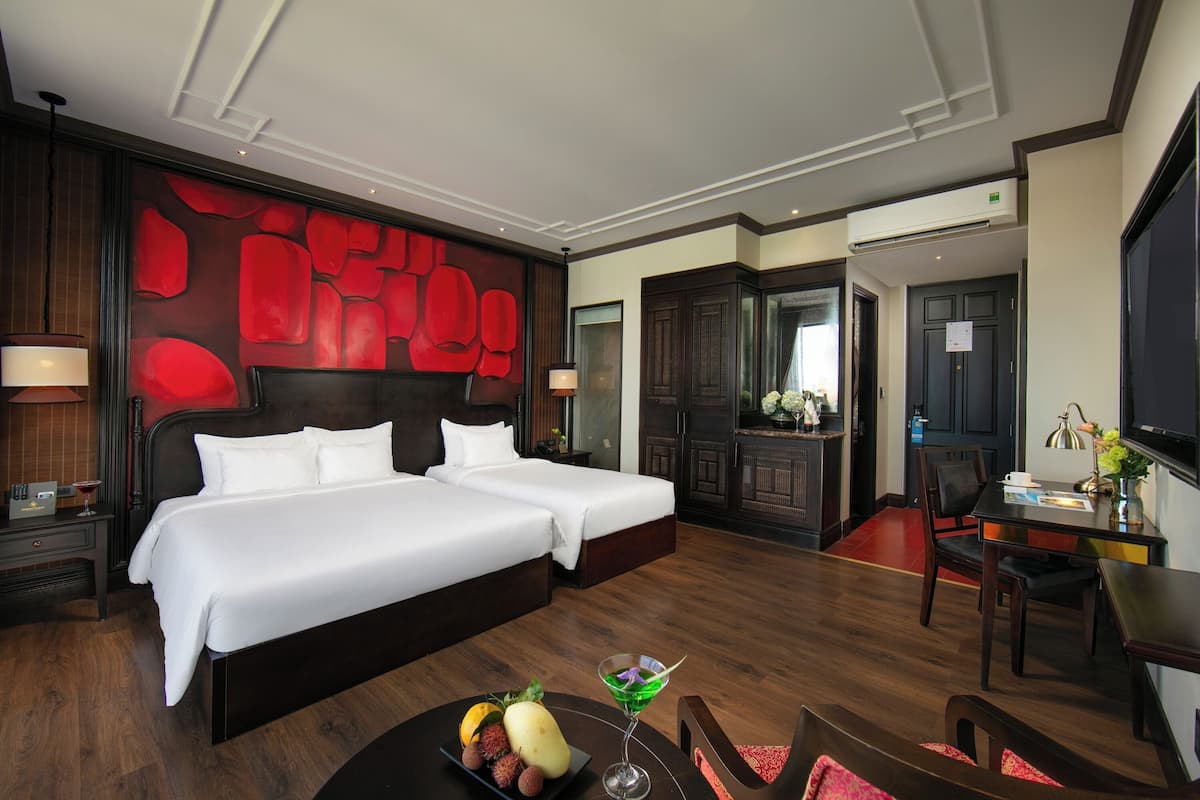 Ein Hotelzimmer mit zwei Betten, einem Essbereich und einem Fernseher.