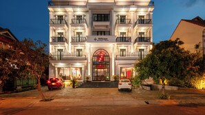 A multi-story hotel with a prominent entrance, balconies, and a well-lit facade. - Silkian Hoian Boutique Hotel & Spa (Da Nang)