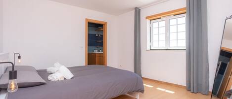 Een moderne slaapkamer met een bed, een kledingkast, een raam met gordijnen en een plafondlamp.