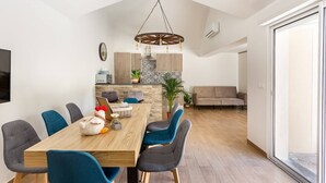 Ein moderner Essbereich mit einem Holztisch, blauen Stühlen und einer hängenden Leuchte.