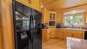 A modern kitchen with wooden cabinets, a black refrigerator, a microwave, and a sink. - Kubo Del Sol - Log Cabin, Hot Tub, Game Room, Pool Table, Ping Pong (Big Bear Lake)