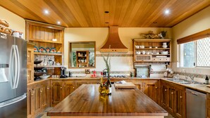 Eine geräumige Küche mit Holzausstattung, einer zentralen Kochinsel und einem Edelstahl-Kühlschrank.