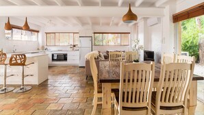 A spacious kitchen with a central island, a dining area with wooden chairs, and a large window providing natural light.