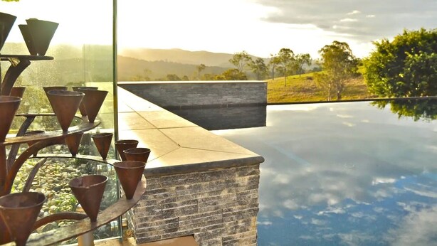 An infinity pool with a stone edge and a metal planter with plants.