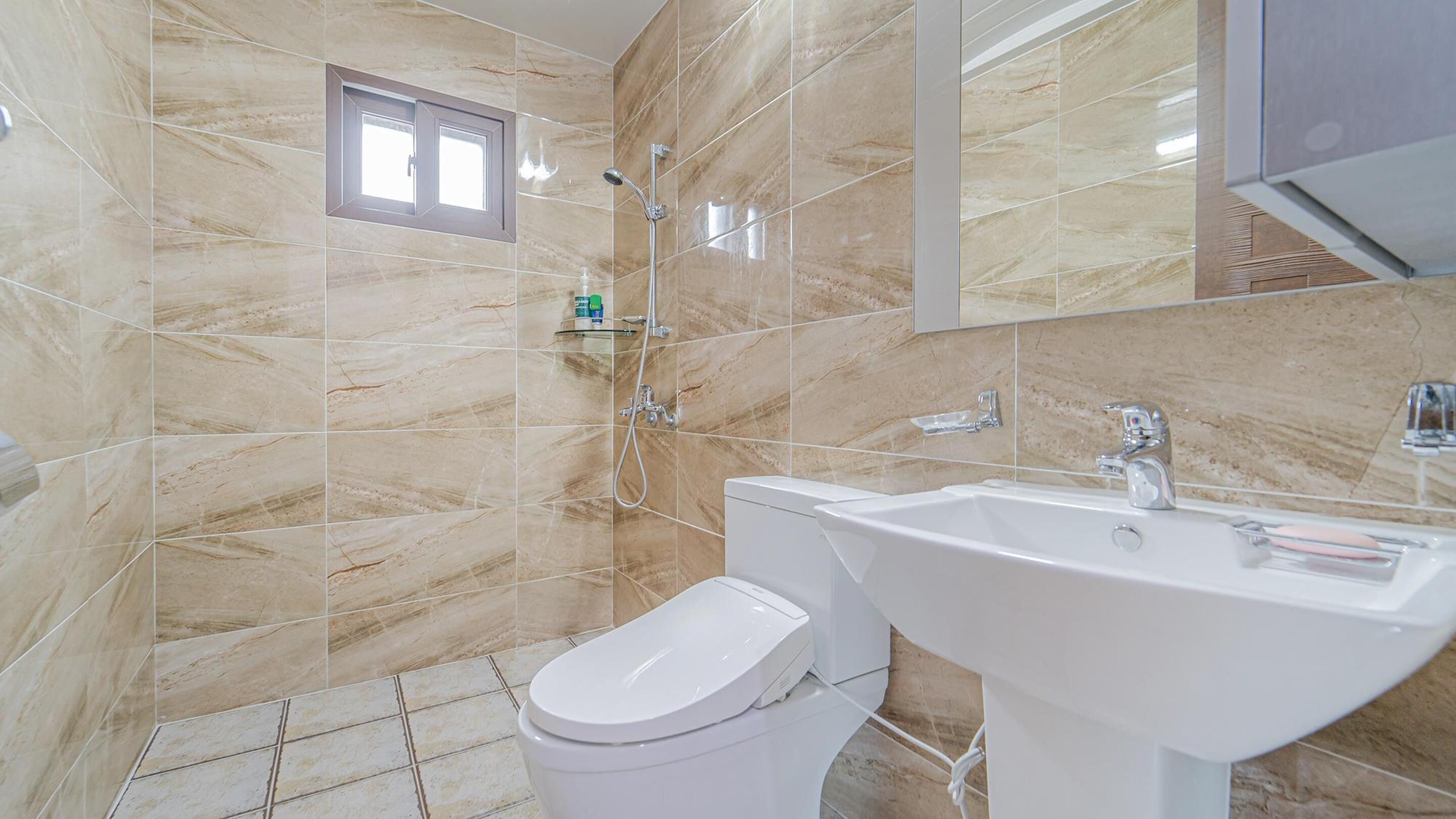 A bathroom with a toilet, sink, and shower.