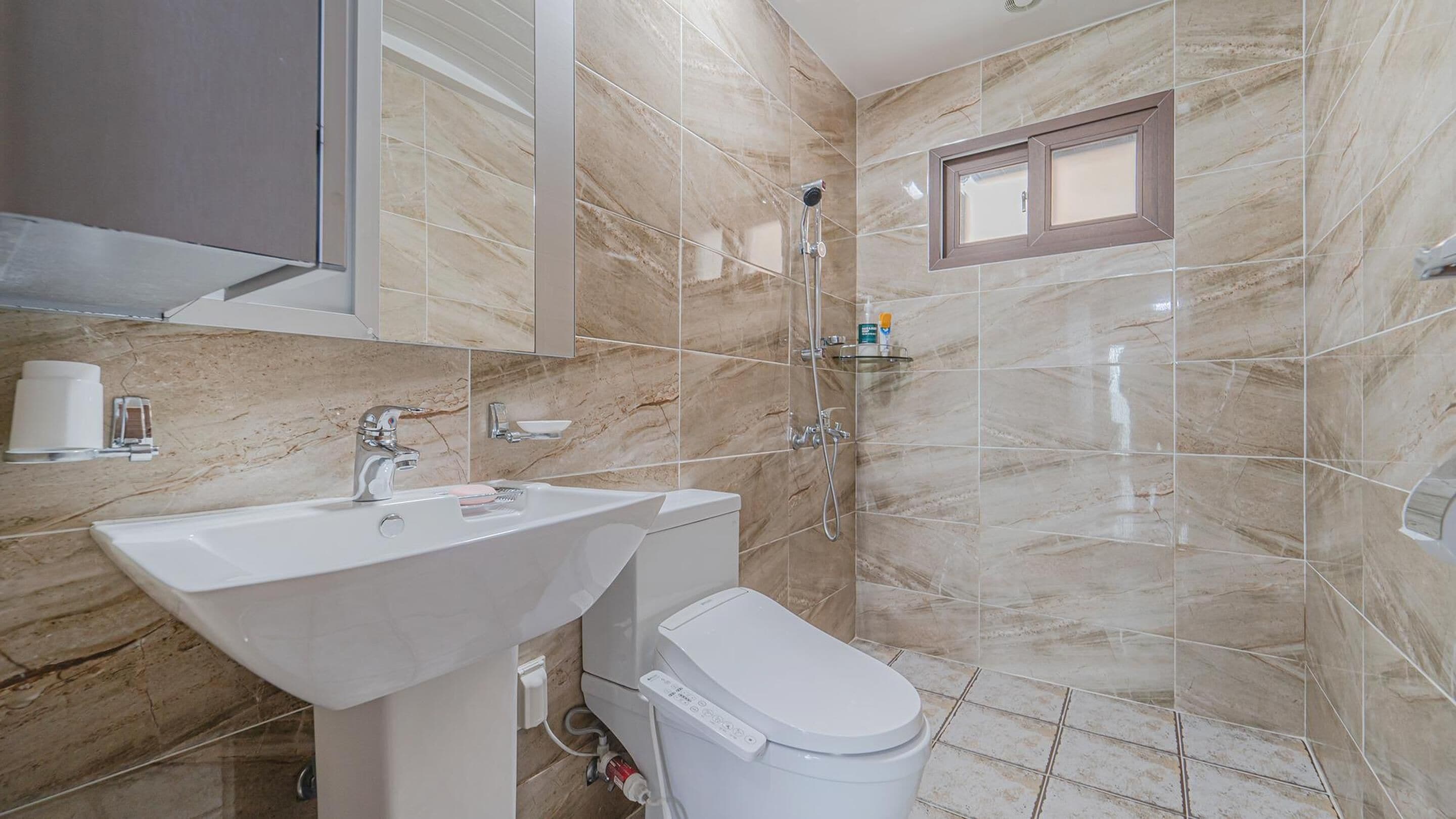 Un baño con lavamanos, inodoro y ducha.