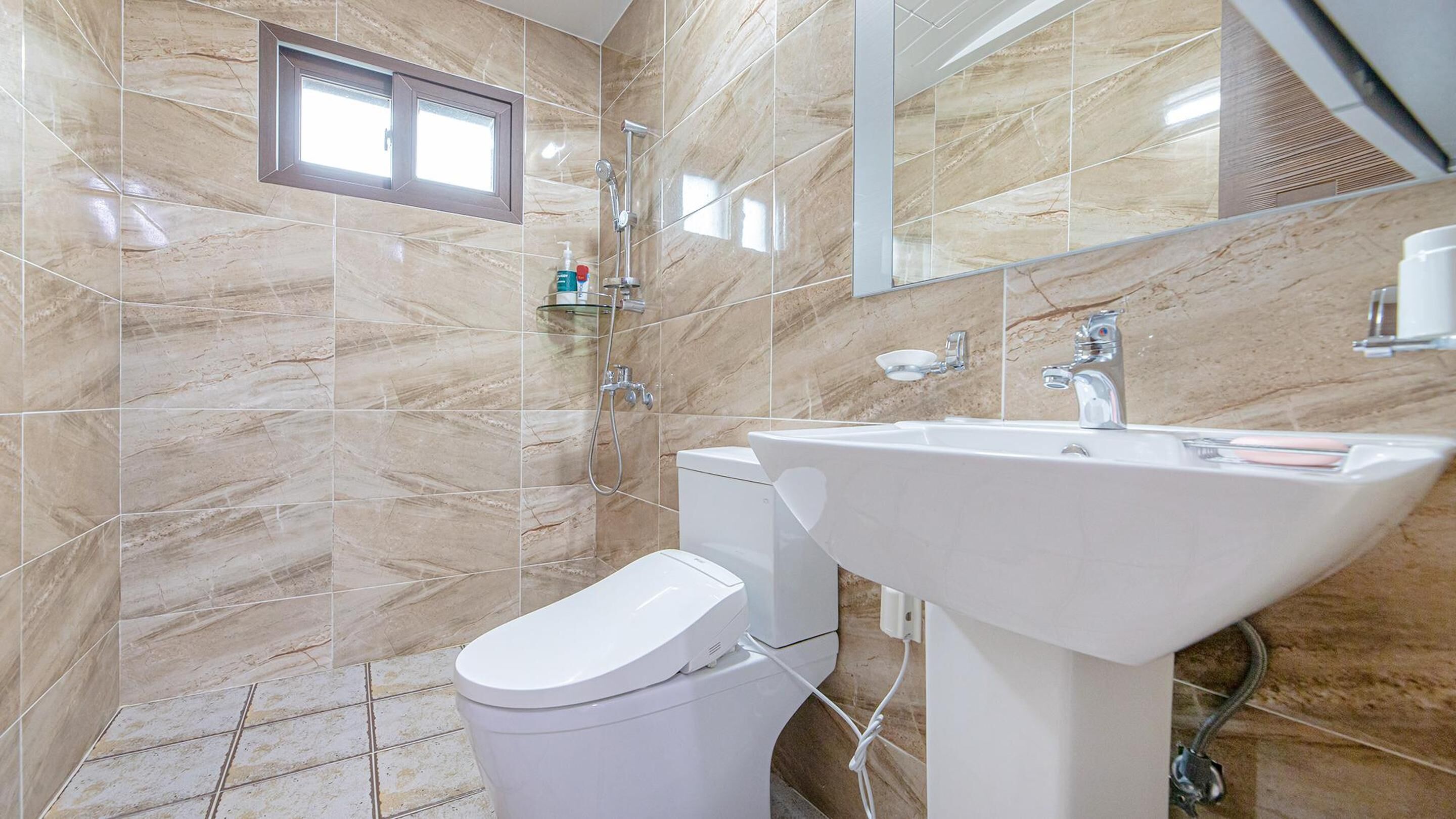 Une salle de bain équipée de toilettes, d’un lavabo et d’une douche.