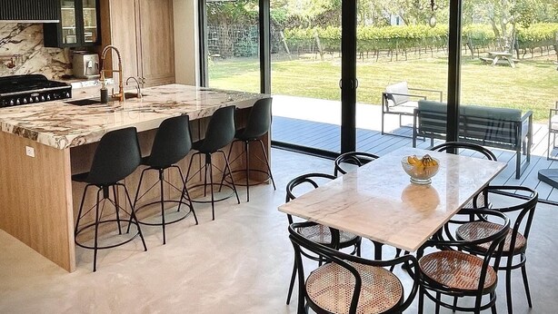 Una cocina moderna con una isla grande, taburetes de bar y un comedor con mesa y sillas.