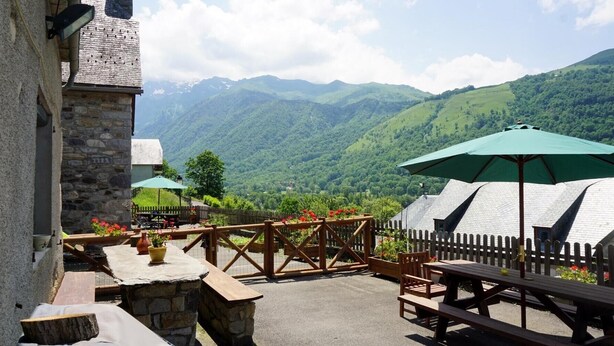 An outdoor seating area with stone tables and benches, surrounded by a wooden fence, overlooking a mountainous landscape. - Gites for 15 people in the Pyrenees, 250m², Loudenvielle (Loudenvielle)