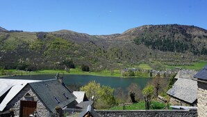 A lakeside view with stone buildings, a clear sky, and a hilly landscape. - Gites for 15 people in the Pyrenees, 250m², Loudenvielle (Loudenvielle)