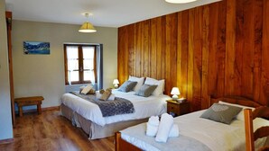 A room with two beds, wooden paneling, a window with curtains, a bedside table with a lamp, and a picture on the wall. - Gites for 15 people in the Pyrenees, 250m², Loudenvielle (Loudenvielle)