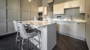 A modern kitchen with a central island, bar stools, and pendant lighting. - Bowers Mill Aparthotel (Halifax)