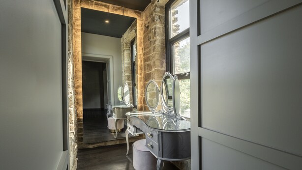 A modern bathroom with a stone accent wall, a large mirror, and a vanity with a sink. - Bowers Mill Aparthotel (Halifax)