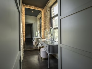 A modern bathroom with a stone accent wall, a large mirror, and a vanity with a sink.