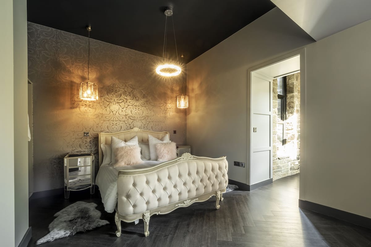 Ein Schlafzimmer mit einem karrierten Kopfteil, zwei Nachttischen und einem großen Fenster.