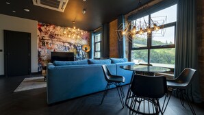 A modern living room with a blue sectional sofa, a round glass table, and black chairs. - Bowers Mill Aparthotel (Halifax)