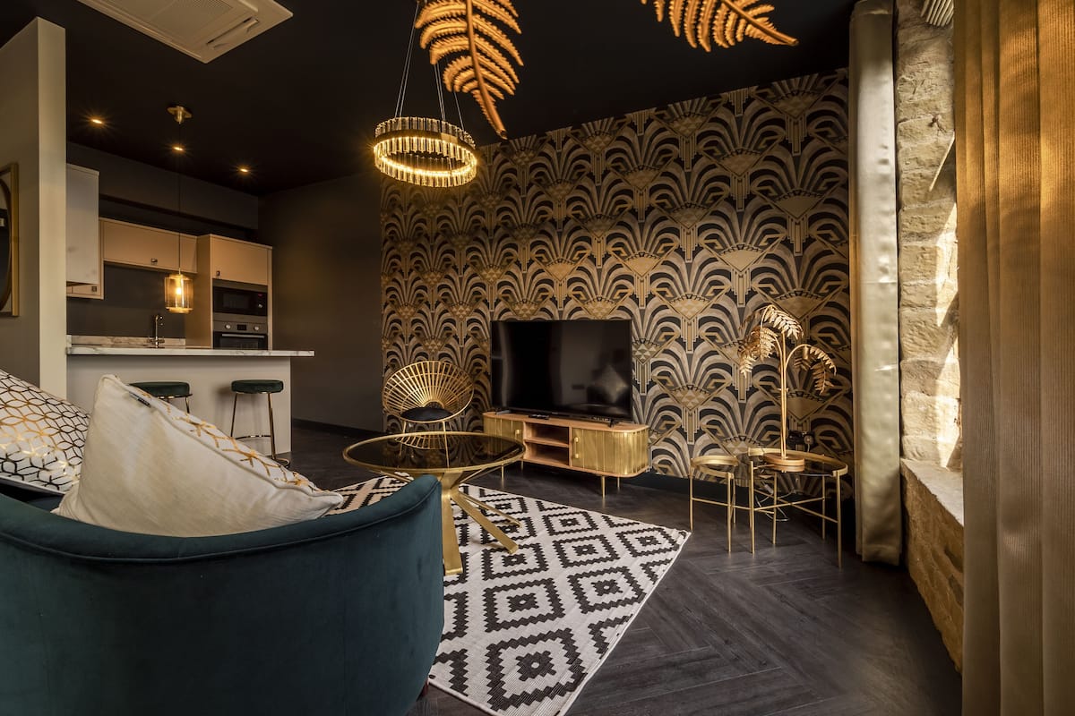 Ein modernes Wohnzimmer mit einer Couch, einem Fernseher, einem gemusterten Teppich und einem einzigartigen Deckendesign.