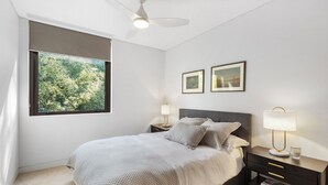 Ein Schlafzimmer mit einem Bett, einem Nachttisch, einer Lampe und zwei gerahmten Bildern an der Wand.
