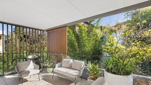 Ein Balkon mit einer Couch, einem kleinen Tisch und einem Grill.
