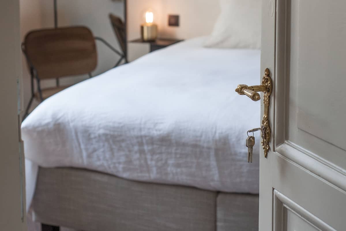 Ein Schlafzimmer mit Bett, Stuhl, Nachttisch, Lampe und Spiegel.