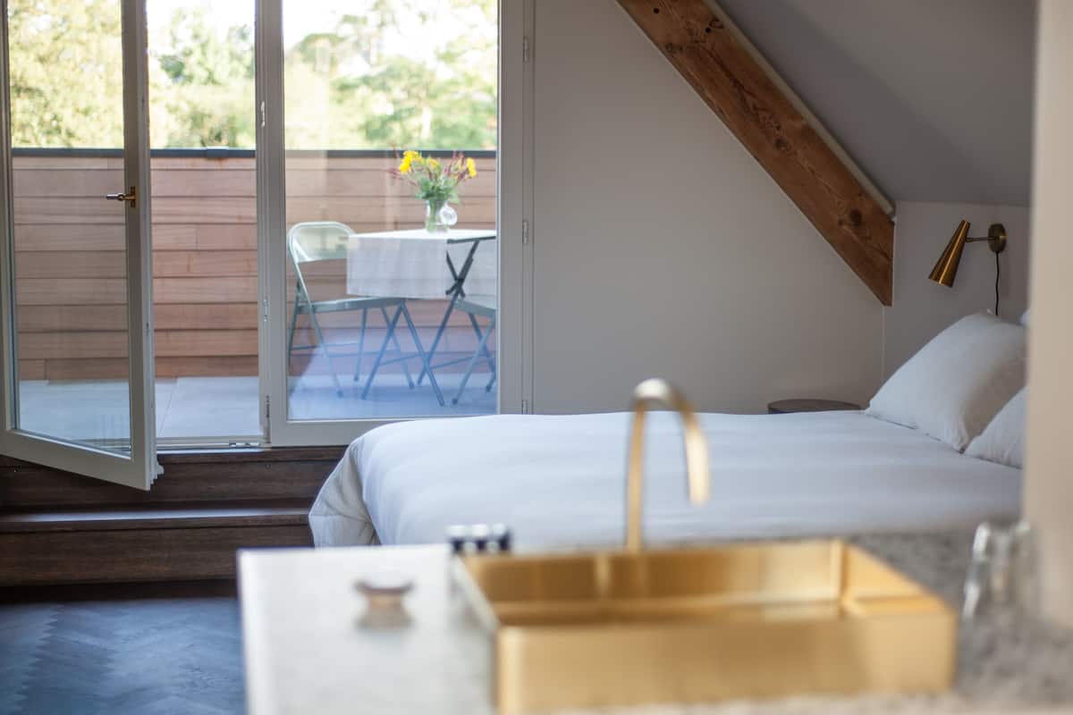 Ein Schlafzimmer mit Bett, einem kleinen Tisch und einem Fenster mit Blick auf einen Balkon.