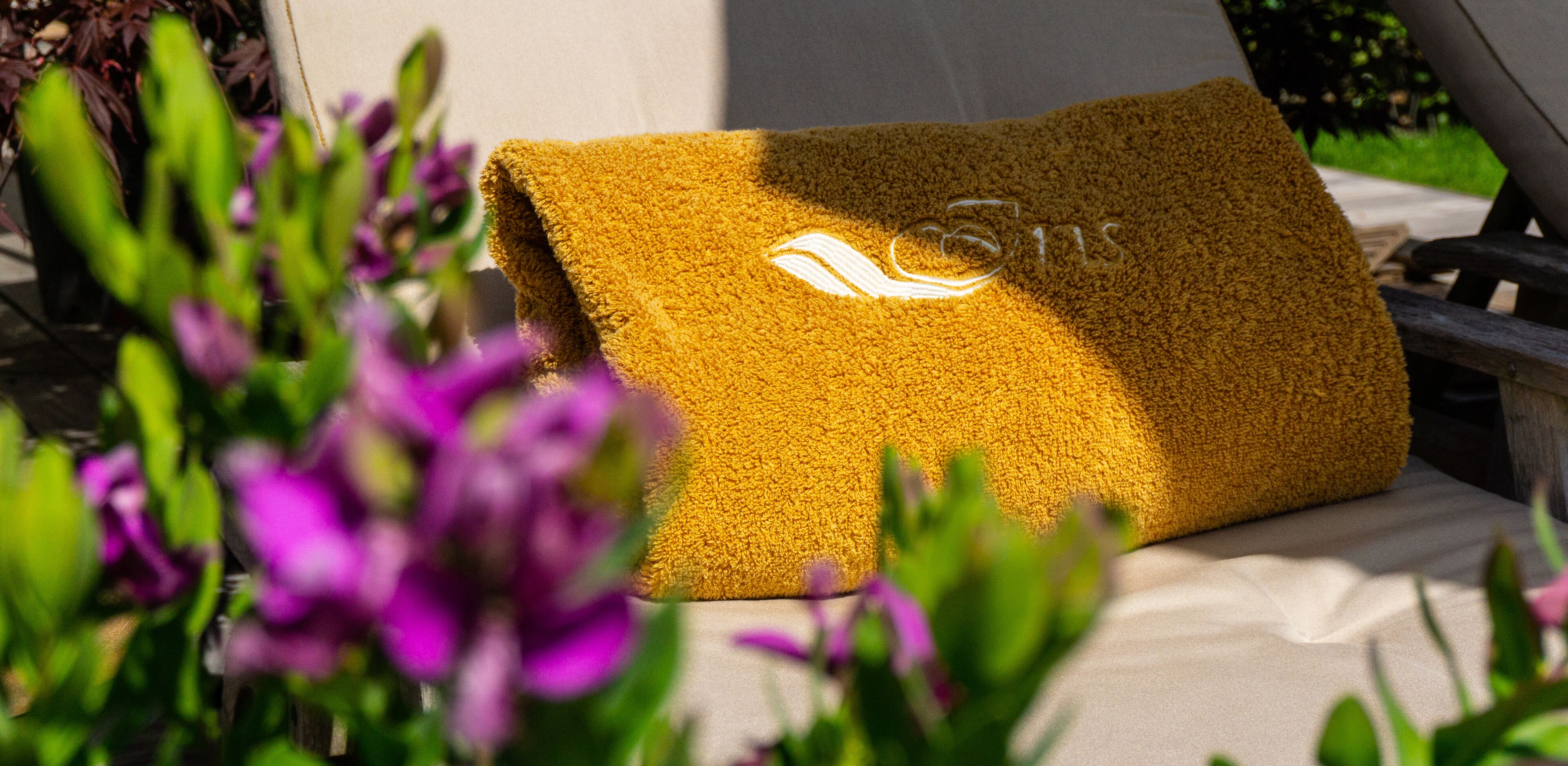 Una toalla doblada con un logotipo sobre una cama en una habitación con vistas a zonas verdes.