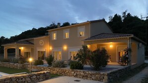 Una casa de dos pisos con fachada de piedra, múltiples ventanas y una entrada bien iluminada.