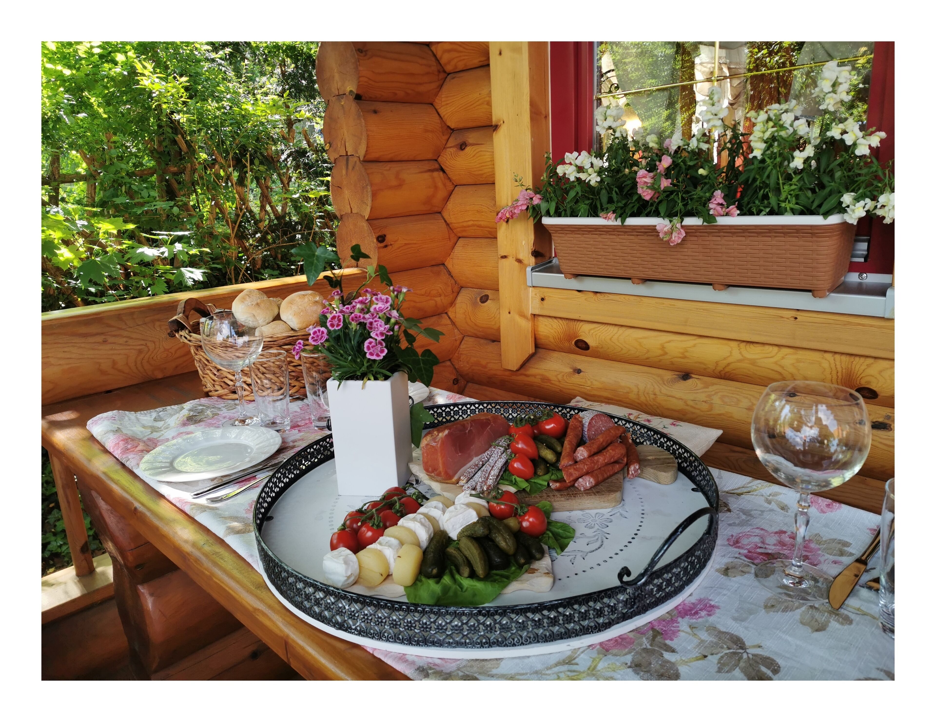 Une table en bois, dressée avec une assiette de nourriture, un verre de vin et un vase de fleurs.