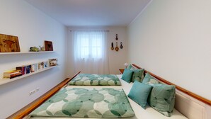 Un dormitorio con dos camas, una estantería y una ventana con cortinas.