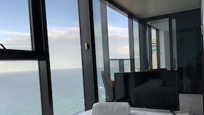 Una habitación de hotel moderna con una cama grande, televisión de pantalla plana y vista al océano.