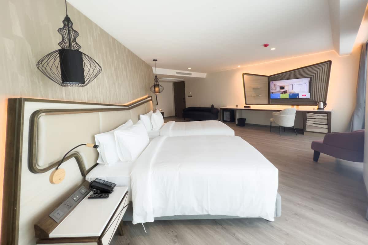 Moderni hotellihuone, jossa on suuri sänky, yöpöytä ja työpiste tuolilla.