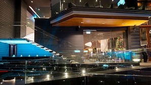 A modern building with a glass facade, a staircase, and a Christmas tree inside. - Amethyst Hotel Pattaya (Pattaya)