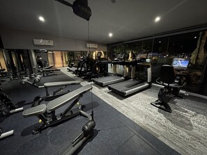 A gym with treadmills, weight machines, and a rowing machine.