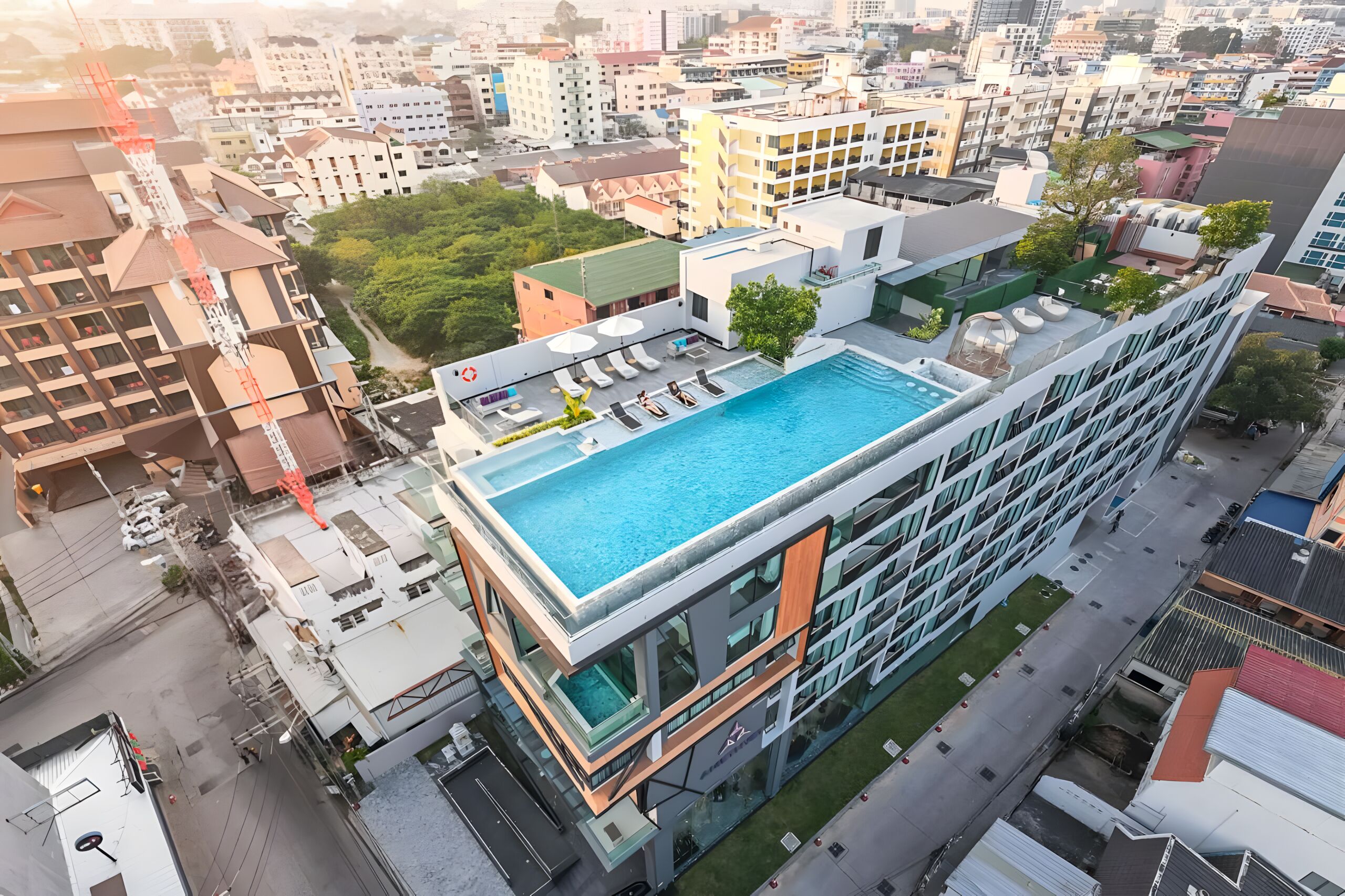 A modern hotel with a rooftop infinity pool, a glass facade, and a central courtyard.