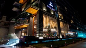 A modern hotel with a prominent sign, a glass facade, and a Christmas tree outside. - Amethyst Hotel Pattaya (Pattaya)