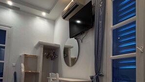 A room with a desk, chair, mirror, and a TV mounted on the wall.