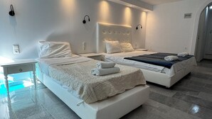 A modern bedroom with two beds, a small table, and a built-in bench.
