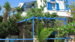 A white building with blue shutters and a blue pergola.