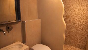 Un baño con lavamanos, inodoro y ducha con un diseño de pared curva único.