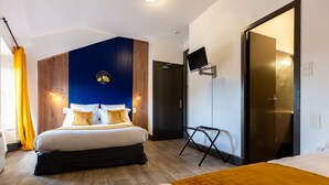 A modern hotel room with a large bed, a TV mounted on the wall, and a wooden floor. - Grand Hôtel 1899 (Langogne)