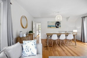A modern living room with a sofa, a dining table with chairs, a wooden cabinet, and a painting on the wall. - Gigglewiggy, Somers. (Somers)