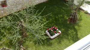 Muro de piedra con jardineras y un pequeño árbol en un patio.