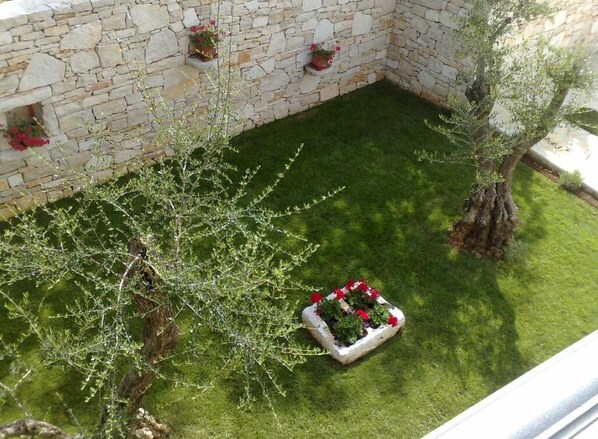 Muro de piedra con jardineras y un pequeño árbol en un patio.