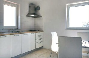 Una cocina con armarios blancos, estufa y ventana.