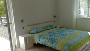 Un dormitorio con cama, mesita de noche y ventana.