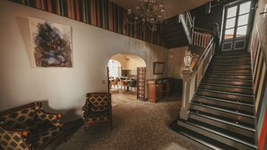 Una escalera que lleva al segundo piso, un comedor con sillas y una mesa, y una alfombra estampada.