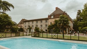 Una piscina con cubierta de madera, rodeada por una valla y árboles.