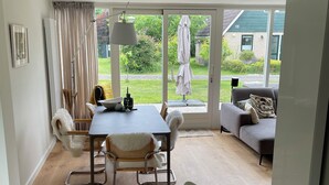 Una sala de estar moderna con comedor, puertas correderas de vidrio que dan a un jardín y un sofá con vistas.